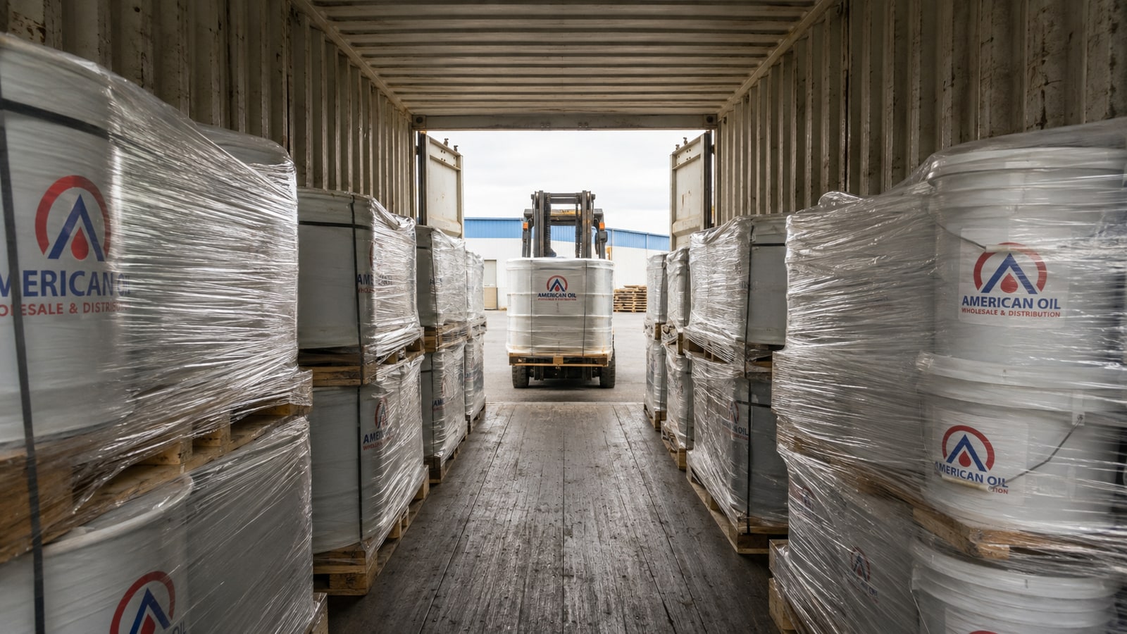 Loaded 40-foot shipping container filled with pallets of motor oil cases, drums, and pails viewed from the open doors